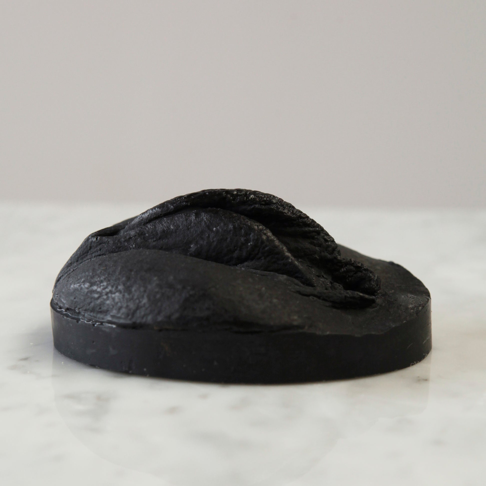 black soap with charcoal and jojoba oil for oily skin, vulva shaped. Seitenansicht der schwarzen Seife, sie ist mit Aktivkohle und Jojobaöl wunderbar geeignet für fettige Haut